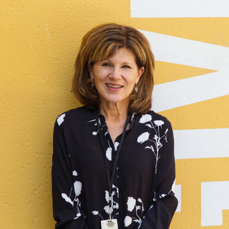 A woman in a black shirt stands in front of a yellow wall